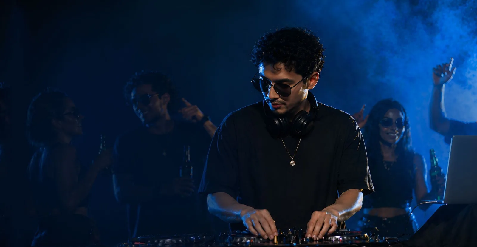DJ performing to a packed crowd under stage lighting