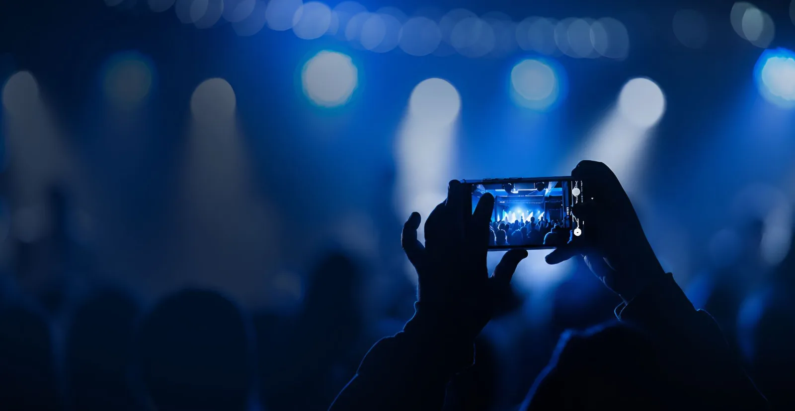 Crowd silhouetted against stage lighting at an event