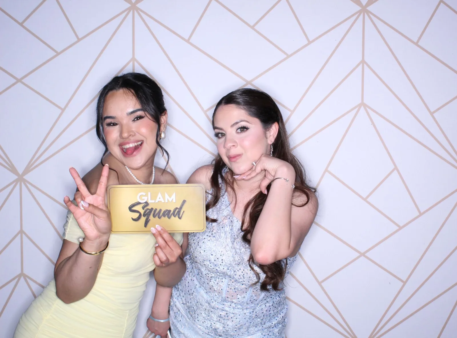 Friends posing at a photo booth with geometric backdrop