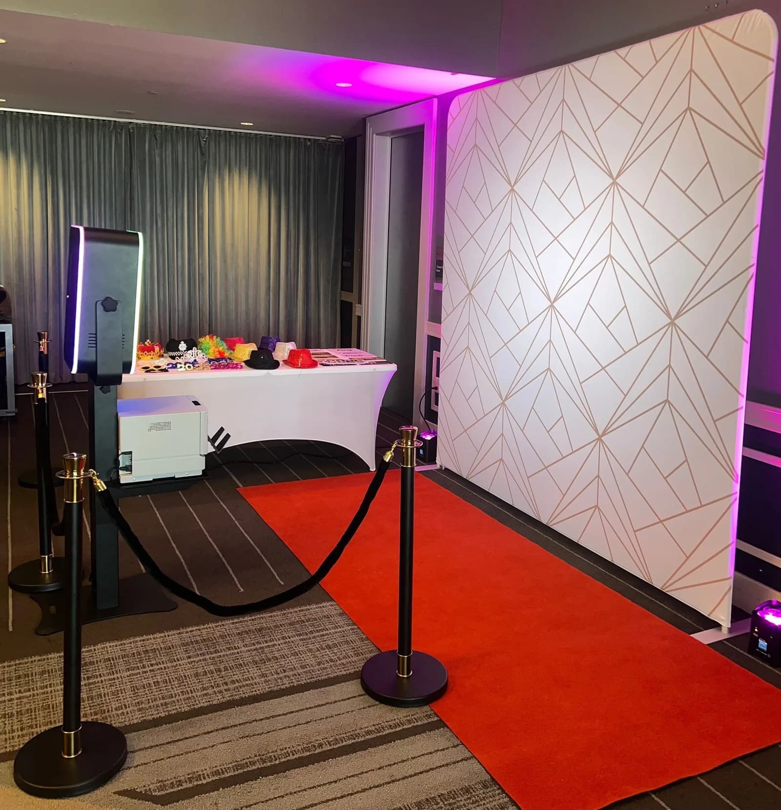 Open-air photo booth with red carpet and stanchions