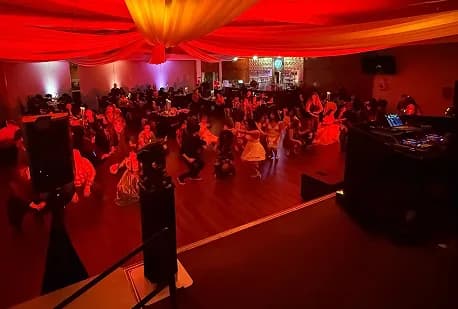 Packed dance floor under red uplighting with draped ceiling