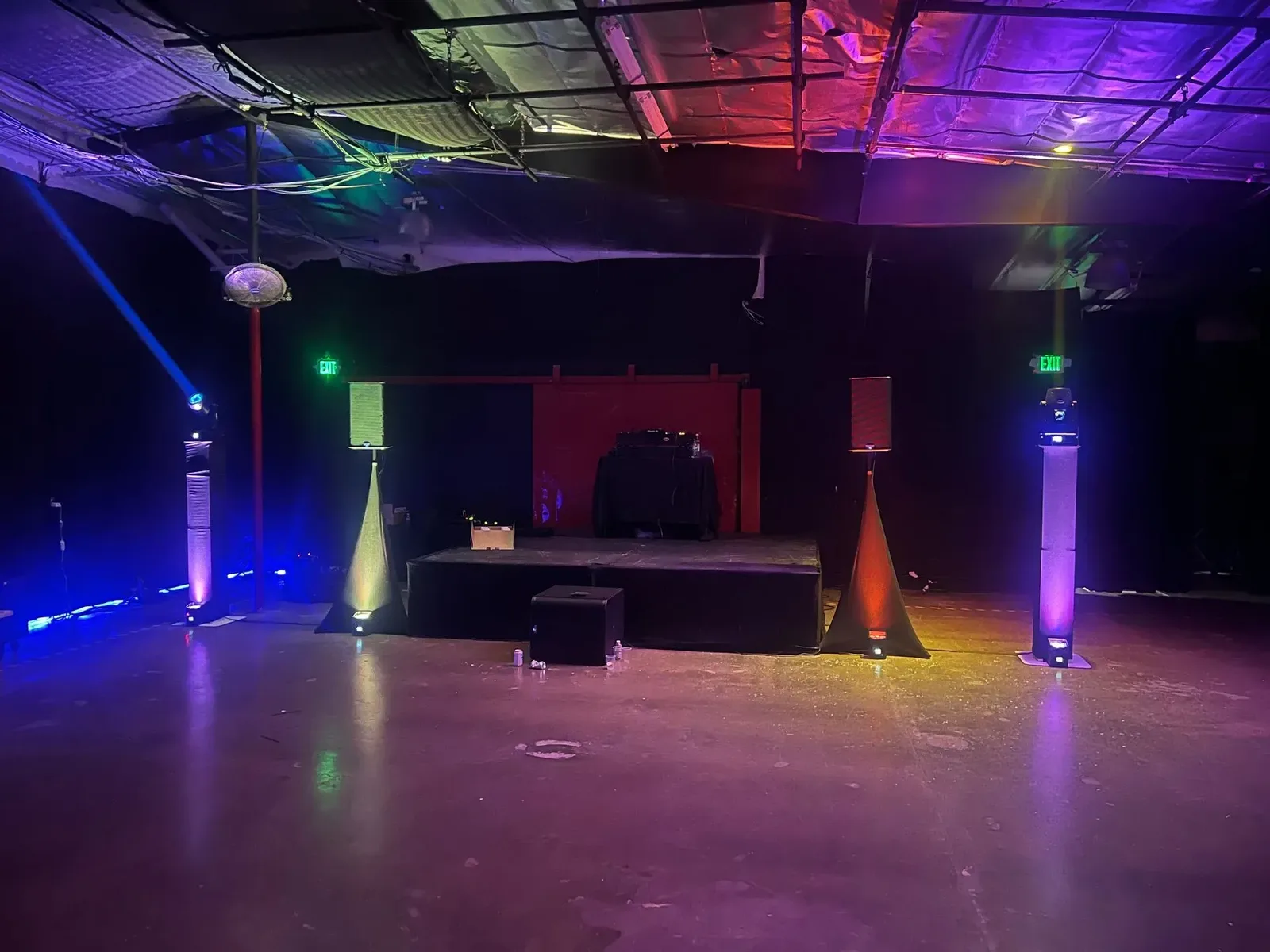Venue washed in blue and purple LED uplighting with a lit stage
